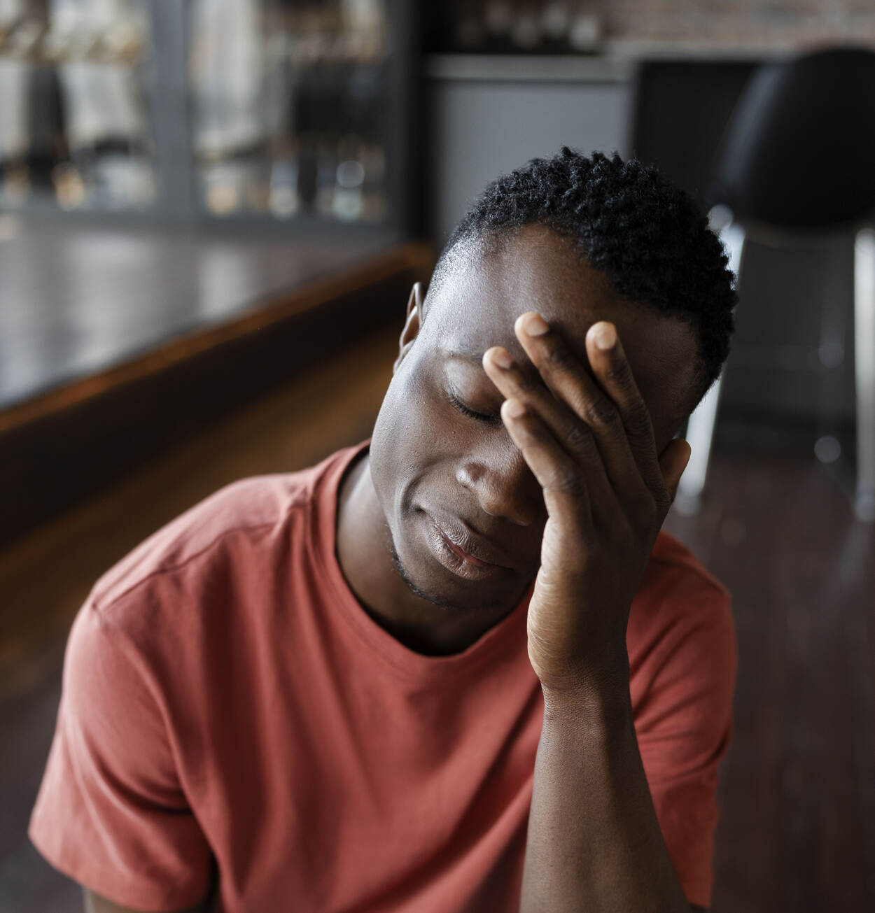 Een man kijkt verdrietig en zit met zijn hand bij zijn voorhoofd