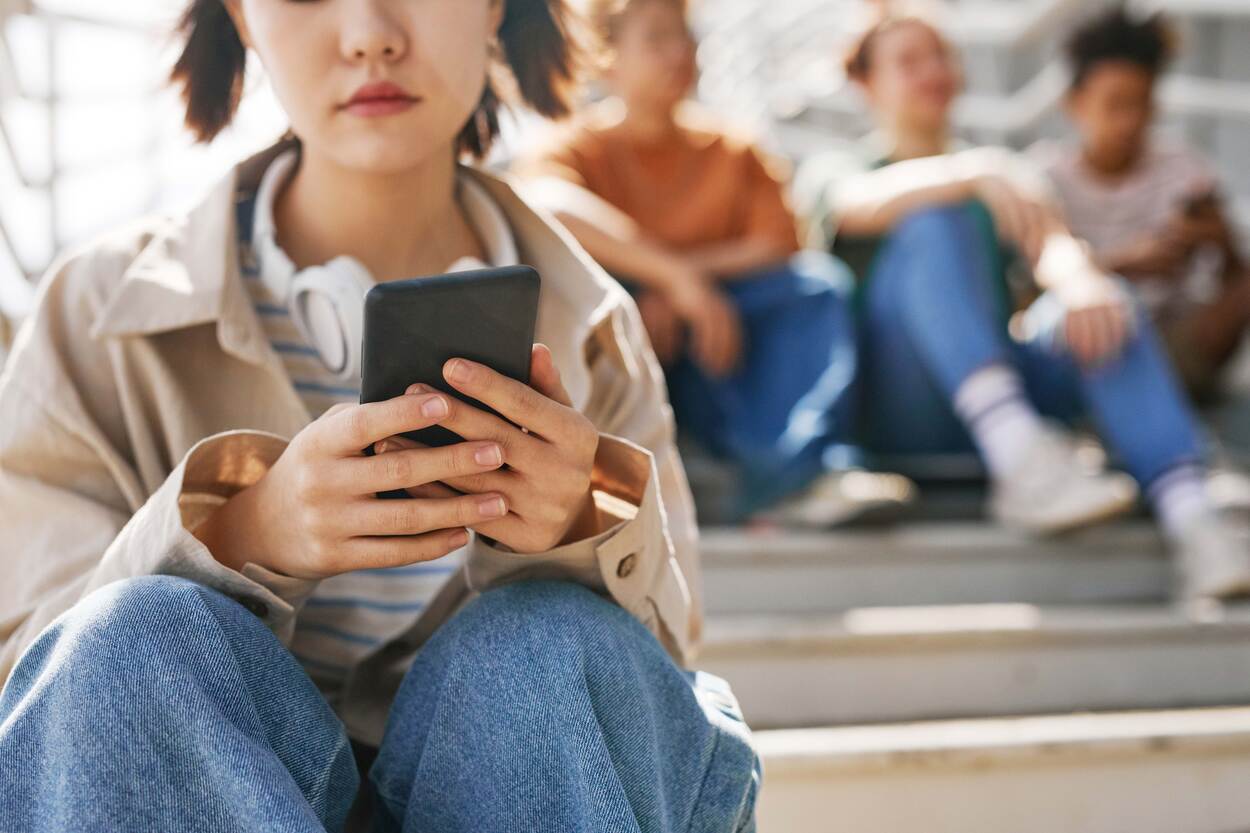 Een meisje heeft een mobiele telefoon in haar hand en zit op een trap