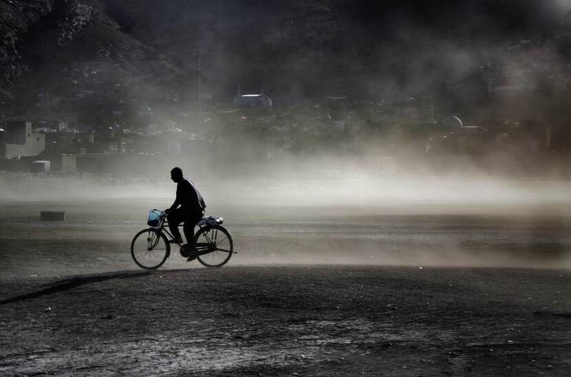 Een man fietst over een vlakte in Kabul, Afghanistan